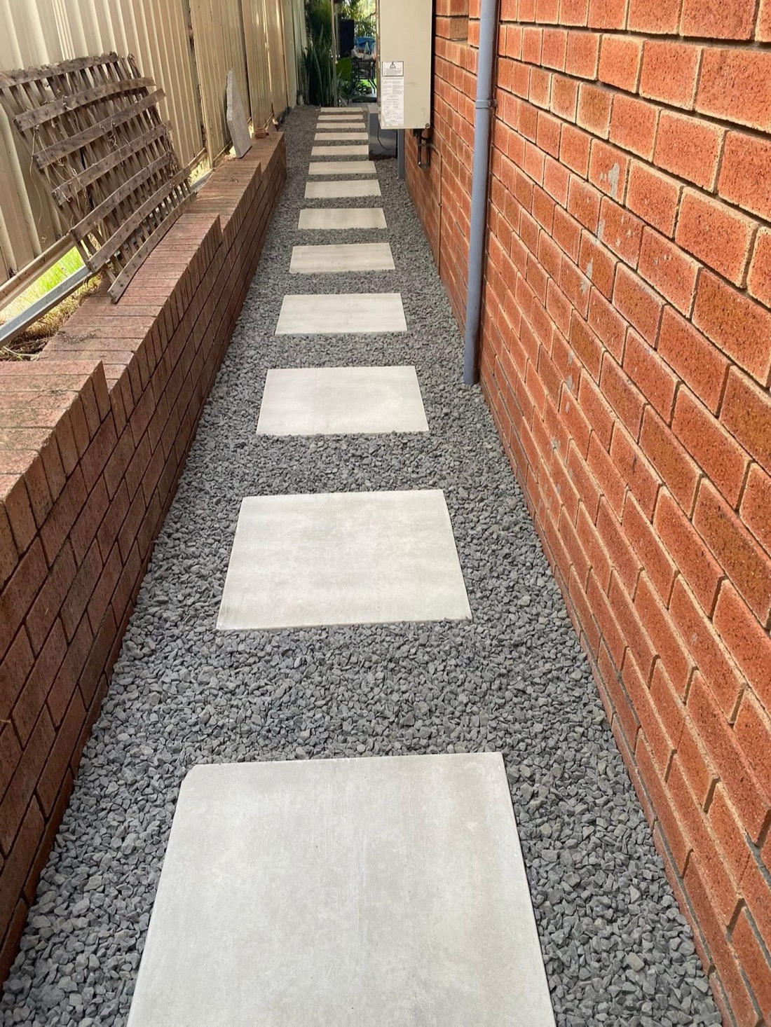 The same side passage finished with large concrete stepping stones set in dark grey gravel, after installation.