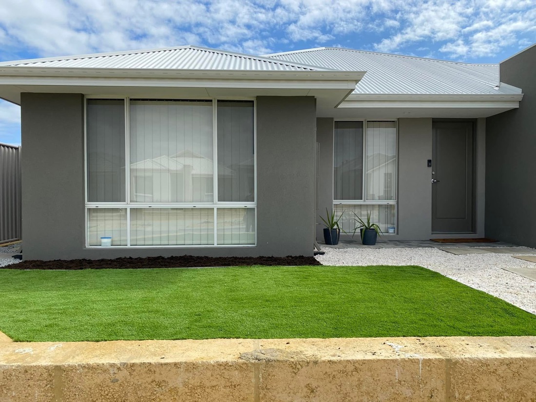 Same new-build frontage finished with a neat lush green lawn and small garden bed, after installation.